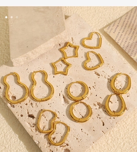 Detailed view of six pairs of gold minimalist geometric earrings on a textured stone surface