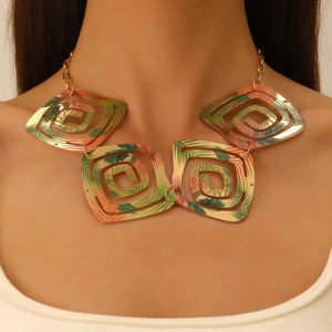 Détail d'un collier doré géométrique avec des motifs de feuilles tropicales en spirale