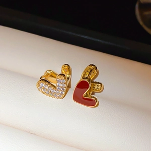 Gros plan de boucles d'oreilles cœur dorées avec émail rouge et zircons brillants