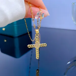 Macro shot of 18K gold plated cross necklace with Hamsa hand and sparkling zircon detail
