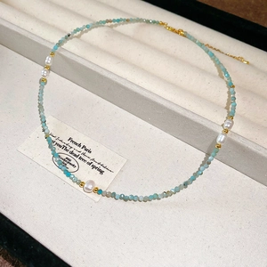 Detailed close-up of light blue amazonite and white freshwater pearl necklace on box