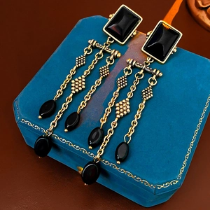 Vintage gold and black tassel earrings displayed on a classic blue jewelry box