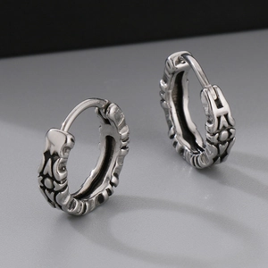 Macro detail of antique silver hoop earrings featuring embossed cross and floral patterns