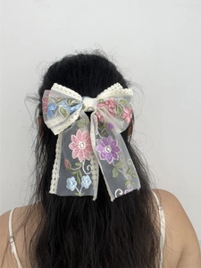 Detailed back view of a large white lace bow hair clip with embroidered floral patterns