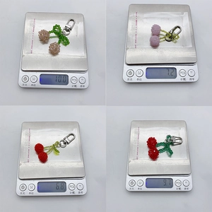 Weight display of four colorful crystal beaded cherry keychains on a digital scale