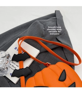 Detail view of pumpkin crossbody bag with quilted faux leather and bat strap charm