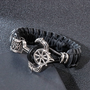 Détail d'un bracelet en cuir tressé noir avec fermoir ancre en métal argenté et gouvernail