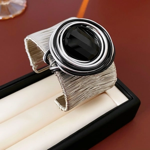 Macro detail of multi-layer silver cuff bracelet with a large black faceted gemstone