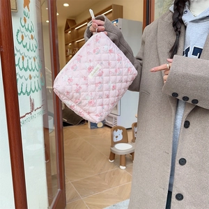 Détail de la trousse de maquillage rose matelassée avec motifs de fleurs et de lapins
