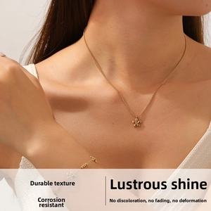 Close-up of gold beaded chain bracelet and flower pendant necklace set on model skin