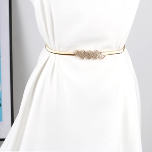 Nahaufnahme eines goldenen elastischen Metallgürtels mit geometrischer Strass-Schnalle auf Kleid