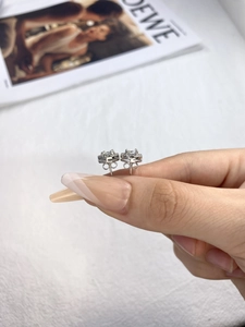 Close-up of sparkling moissanite stud earrings in 925 silver held by hand for scale