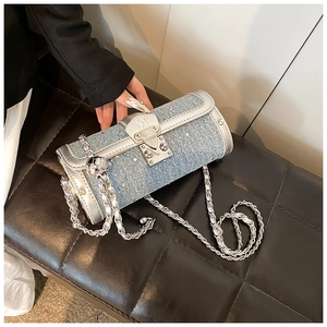 Close-up of blue denim cylinder bag featuring sparkling rhinestones and silver chain strap