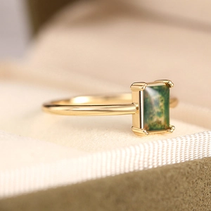 Macro detail of gold ring featuring rectangular green moss agate in four-prong setting