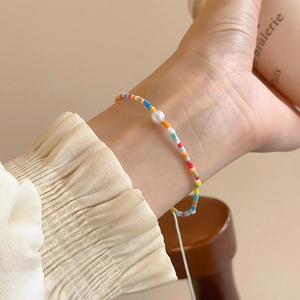 Close-up of colorful beaded star bracelet with a white pearl on a model's wrist