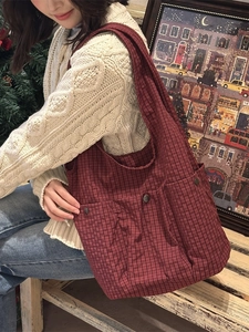Large red checkered tote bag with three front pockets shown in a winter setting