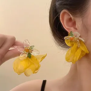Détail de la boucle d'oreille fleur en tulle jaune avec des perles en résine