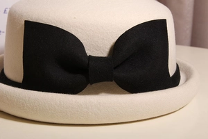 Detailed texture of ivory wool felt cloche hat with a large black bow accent
