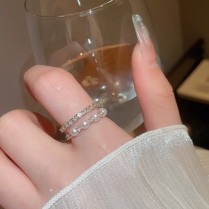 Detail of layered gold ring with delicate pearls and crystals on a model hand