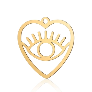 Macro shot of gold heart-shaped pendant with evil eye cutout on white background
