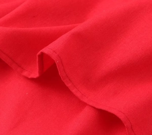 Détail macro du tissu en coton rouge avec couture d'ourlet précise sur la robe