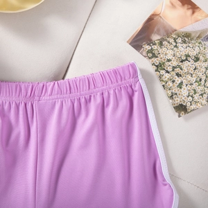 Detail of purple sports shorts showing elastic waistband and white contrast piping finish