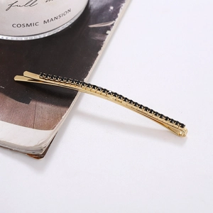 Detail of long gold hair clip with black rhinestones on a stylish magazine background