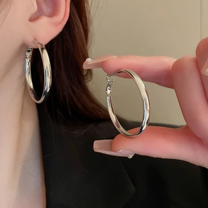 Macro shot of mirror-polished silver geometric hoop earring showing secure plug-in clasp