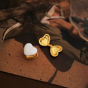 Detail of white enamel heart earrings on gold plated copper with a polished finish