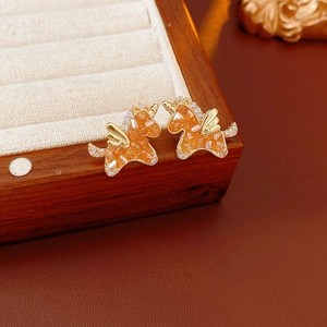 Close-up of golden unicorn earrings with orange crystals and sparkling zircons