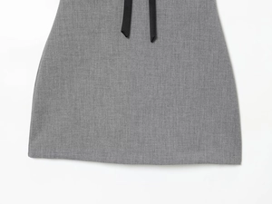 Detailed view of grey woven fabric texture with decorative black ribbon waist tie detail