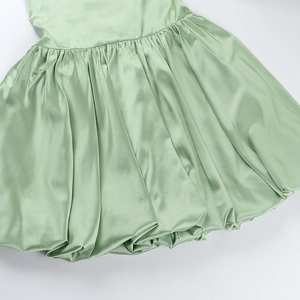 Detail of light green satin dress featuring elegant pleats and ruched fabric texture