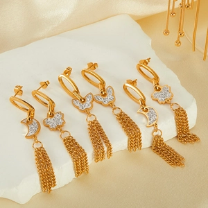 Macro shot of gold tassel earrings with butterfly and moon motifs inlaid with white zircons