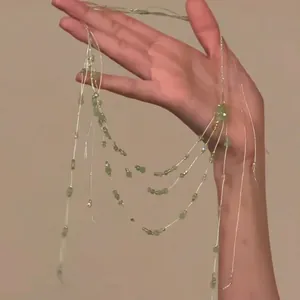 Détail d'un collier multi-rangs avec perles vert clair et cristaux sur chaînes fines