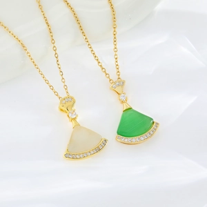 Gold fan-shaped necklace with white and green stones on white silk background