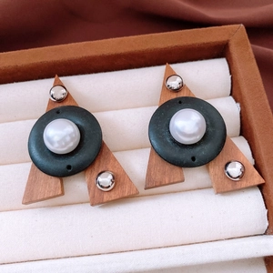 Detail of geometric wood triangle earrings with black patch and center faux pearl