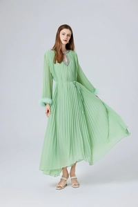 Détail de robe longue plissée vert menthe avec poignets en plumes et col en strass