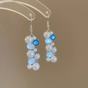Detail view of elegant drop earrings featuring blue cat eye stones and white pearls