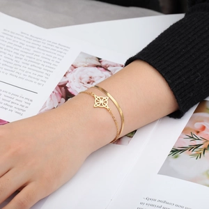 Close-up of double-layered gold snake chain bracelet with geometric hollow pendant
