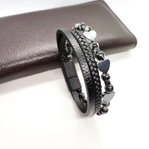 Dettaglio di un bracciale multistrato in pelle con ciondoli a cuore e chiusura magnetica