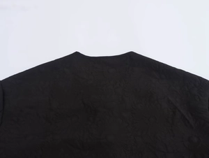 Detailed close-up of quilted floral texture on a black round neck jacket for women