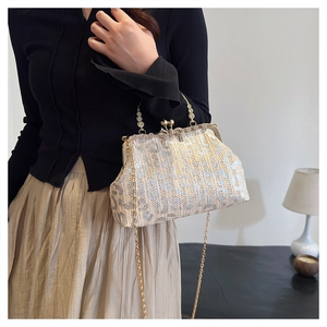 Close-up of a woven dinner handbag with a gold chain strap and pearl handle detail
