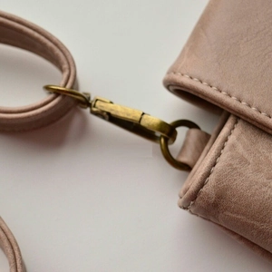 Detail of dusty pink PU leather bag featuring vintage gold metal buckle and stitching