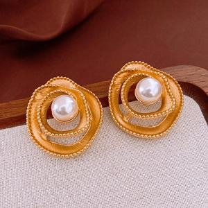 Close-up of vintage gold flower earrings with matte finish and center pearl inlay