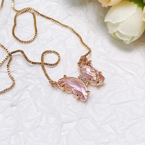 Macro detail of butterfly pendant with pink drop-shaped crystals and rose gold chain
