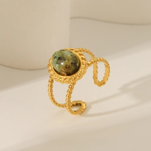 Macro detail of gold vintage ring featuring green natural stone and twisted texture