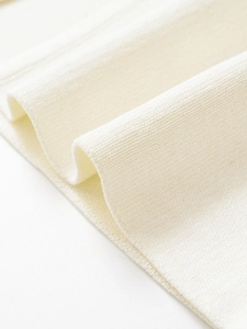 Close-up of cream knit fabric showing high-density ribbed texture and soft material