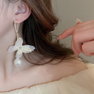 Detailed view of elegant mesh butterfly earrings with pearls and rhinestones on a model