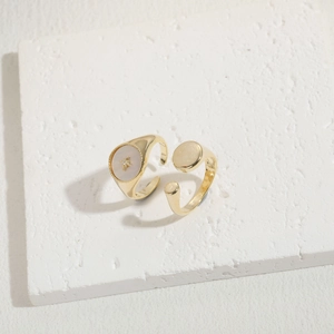 Golden open ring with shell inlay and zircon star detail on white textured stone