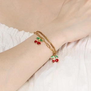 Close-up of double-layer gold chain bracelet with vibrant red cherry charms for women